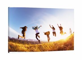 Group happy friends runs and jumps mountains sunset