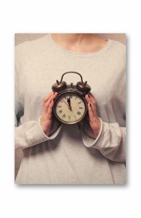 beautiful young woman hands holding a vintage alarm clock on the wonderful grey background