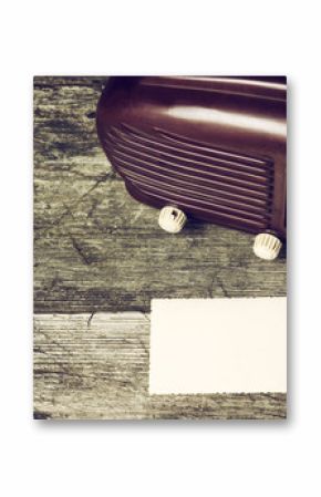 Vintage photo of old radio standing on the old wooden desk. Blank old photo is lying in front of the radio. Suitable for your text. All potential trademarks are removed and blurred.