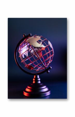 Close up metallic model of a globe with map in blue and red neon light. Bipolarity of the world. Geography concept. Vertical card. Selective focus, Copy space.
