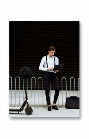 Stylish businessman working on laptop in city