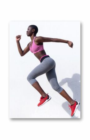 Female runner jumping while practicing against white wall