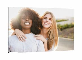 Young multiethnic female friends hugging each other in the city