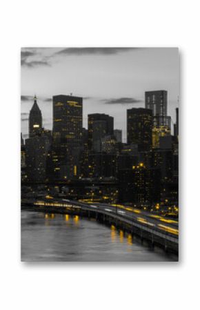 Yellow lights shining in black and white cityscape with the downtown Manhattan skyline buildings of New York City at night time