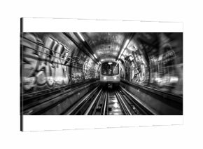 A dynamic view of a subway train emerging from a graffiti-covered tunnel in black and white, capturing urban transportation energy.