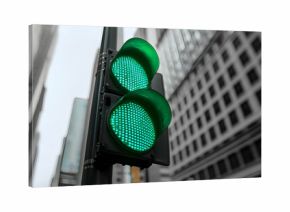 A neon green traffic light shining in a black and white city intersection