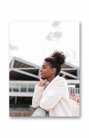 Woman in a white jacket strolling in an urban environment with modern architecture