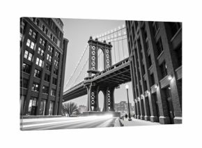 Stunning black and white view of Manhattan Bridge, showcasing its architectural beauty amidst urban buildings. scene captures serene winter