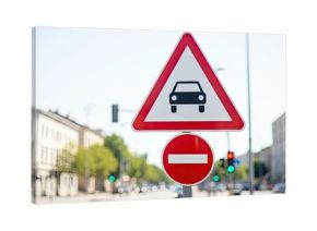 A red and white triangular road sign with a black car icon on a city street.