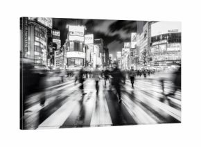 A bustling pedestrian crossing during rush hour, with blurred figures and a sense of motion and urgency, in black and white.