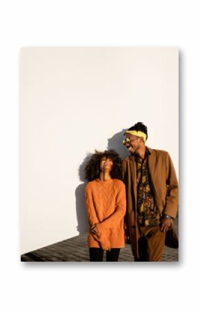 Modern black man and woman against white wall in sunset