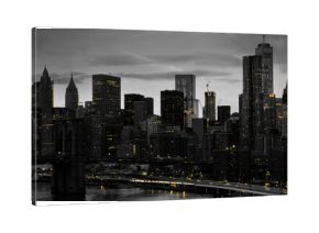 Yellow lights shining in black and white night time cityscape with the Brooklyn Bridge and buildings of Manhattan in New York City