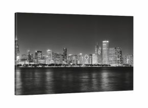 Black and white panoramic picture of Chicago city skyline with reflection in Lake Michigan at night.