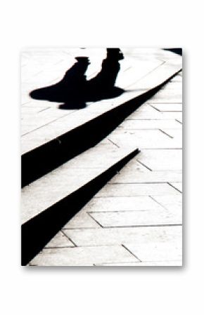 Blurry silhouette shadow of a man walking on a city sidewalk with steps  in black and white