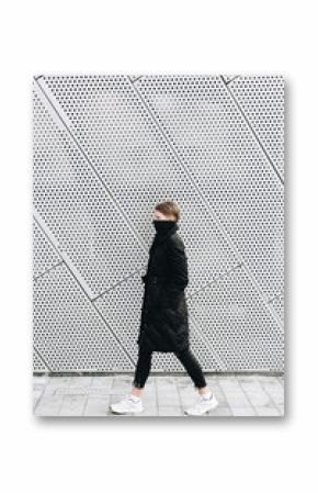 Woman in black coat against metal wall