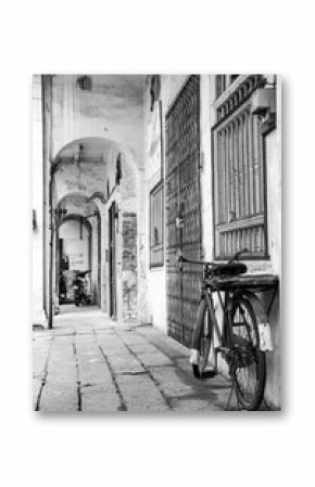Monochrome photo of retro bicycle in a narrow alley, old town