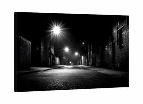 A black and white street at night.  Urban alleyway