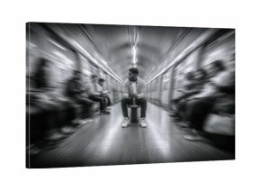 Monochrome Image of a Man Sitting Alone in a Subway Car with Blurred Passengers