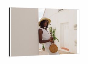 Fashion portrait of stylish black woman in town with white buildings