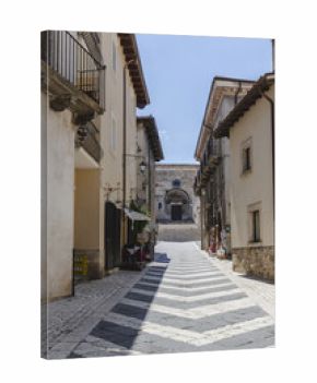 View of an inviting cobblestone street paved with a striking black and white chevron pattern, leading to a church in Pescocostanzo, Abruzzo, Italy.