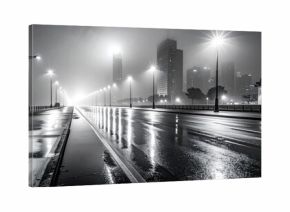 Empty city street with light reflections on a foggy night in black and white