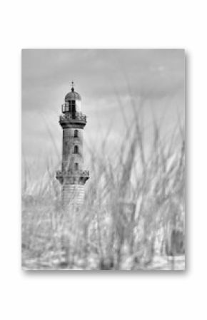 Grayscale shot of the Warnemunde lighthouse with long grass leaves in the foreground