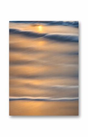 Smoothly blurred sky over a sun-kissed calm sea, golden sands of a tranquil beach in the foreground