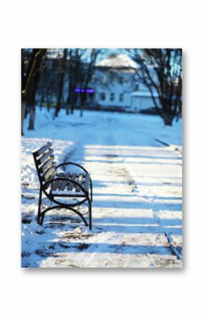 Empty Park Bench in Snow-Covered Winter Landscape on a Sunny Day