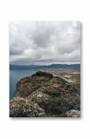Scenic view from a rocky outcrop overlooking a coastal landscape under cloudy skies