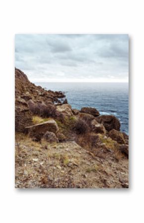 Rugged coastline with rocky cliffs and calm ocean under cloudy sky during the day