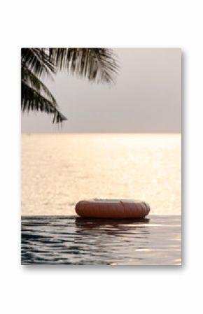 Inflatable circle floats on the pool at sunset, Surround tropical decor and greenery palm tree, Relaxing summer holiday, Inflatable ring float on water sunset view, Summer background vacation leisure.