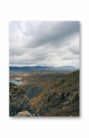 Expansive mountain landscape featuring rugged terrain and distant hills under a cloudy sky