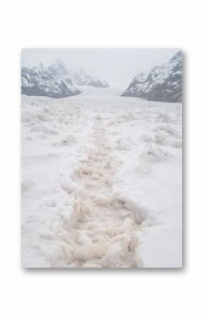 Footprints in Snow Leading Towards Glacial Mountains Under Grey Sky