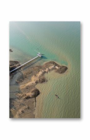 Aerial view of tropical sailboats in a turquoise bay near the harbor, boats floating in crystal clear water near a scenic Thai island with rocky beach. Picturesque shoreline with fun activities.