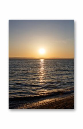 The sun is setting over the ocean, casting a warm glow on the water