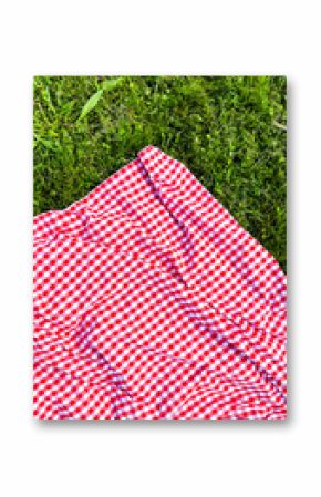 Red checkered picnic blanket on lush green grass in a park setting