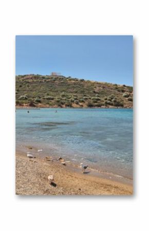 Beach in Attica, Greece, on a sunny day, with temple of Poseidon in the background