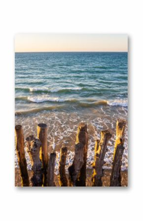 Wooden breakwaters on beach at sunset, Saint-Malo, Brittany, France – vertical photo