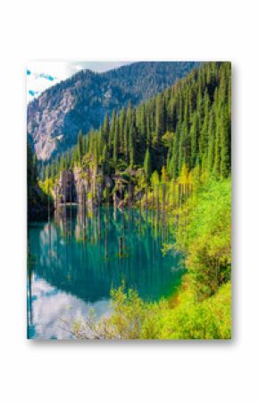 Sunken forest of Lake Kaindy in Kazakhstan. Beautiful mountain natural landscape. A blue lake with tree trunks sticking out of it. Panoramic view of the reserve.