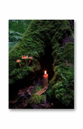 witch amulet and burning wax candle in mystery dark forest, abstract nature background. magical candle for witchcraft, esoteric ritual. mysterious fairy tale scene