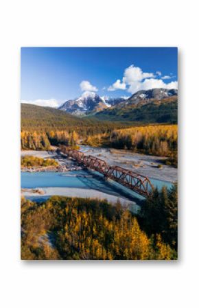 Aerial scenic view of rail road bridge over glacial river in Alaska during autumn time.
