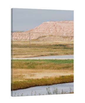 A large red potash mine tailings pile behind a small industrial building and water ponds under cloudy skies in Saskatchewan, Canada.