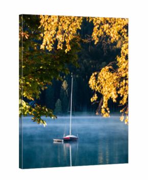 early morning autumn fog and sailboat on the lake