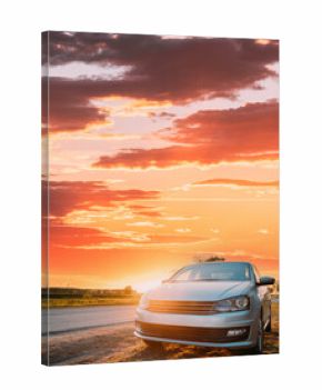 Sedan Car Parking Near Asphalt Country Road In Sunny Sunset. Sunlight Above Road In Sunrise