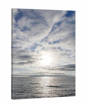 A calm ocean with a bright sun shining on the water