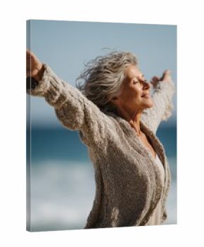 happy mature woman with arms outstretched feeling the breeze at beach beautiful middle aged woman with arms up dancing on beach mid lady feeling good and enjoying freedom at sea copy space no logos n