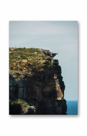 rock cliff edge along the headland with the sea in the background and heath vegetation growing