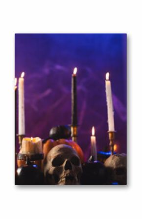 Vertical image of pumpkins, skulls and candles with copy space on purple background
