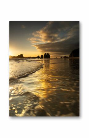 Breathtaking sunrise at Narooma, with golden light reflecting off the gentle waves and the dramatic silhouette of rocky formations in the distance.