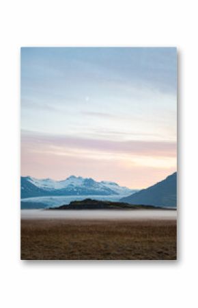 Stunning view of a dramatic landscape with some snowy mountains and a glacier in the distance during a beautiful sunrise, Iceland.